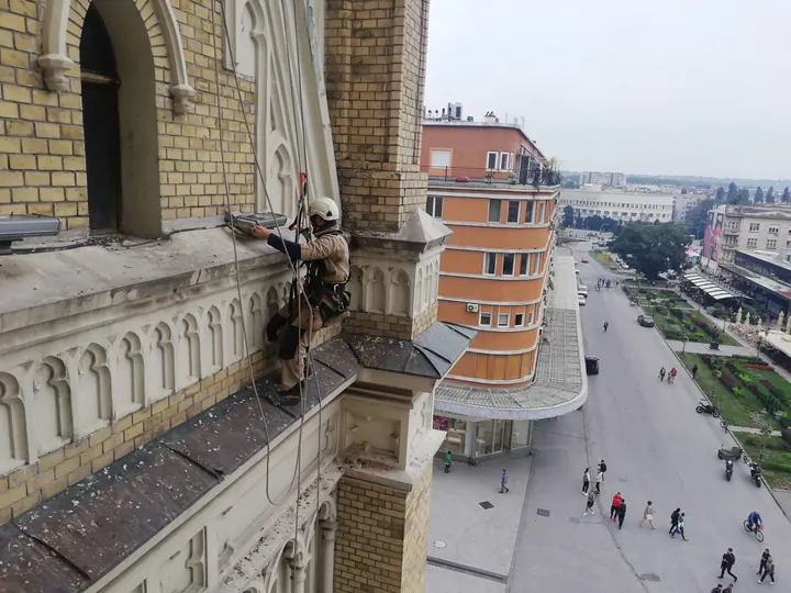 Radnik na užetu uz fasadu iznad ulice